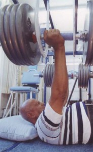 Sri Chinmoy performs a bench press lift